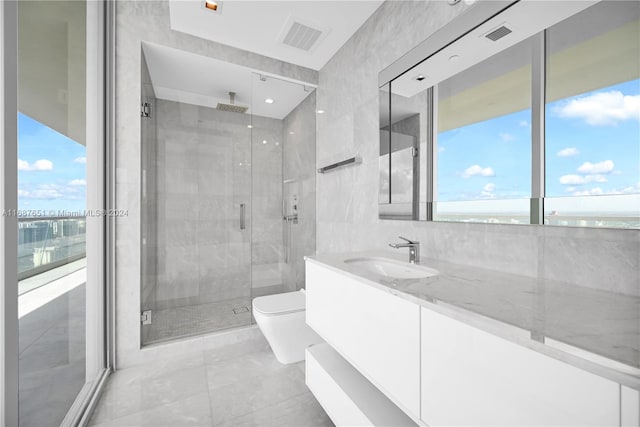 bathroom featuring toilet, a wealth of natural light, vanity, and a shower with door