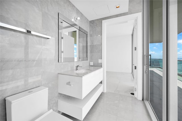 bathroom with a shower with shower door, vanity, and tile walls