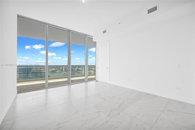 empty room featuring expansive windows, a water view, and a healthy amount of sunlight