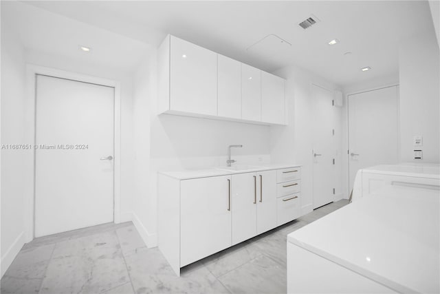 kitchen featuring white cabinets, sink, and washer / clothes dryer