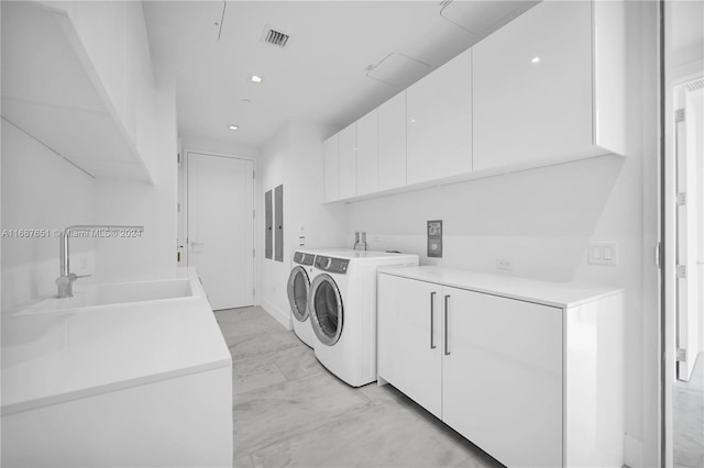 laundry room with electric panel, washing machine and dryer, cabinets, and sink