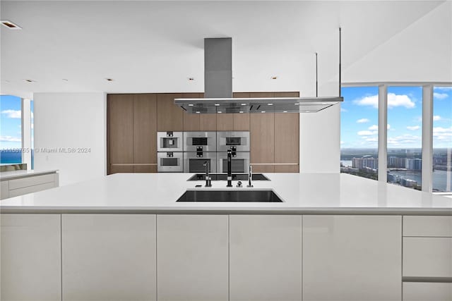 kitchen featuring white cabinetry, a spacious island, sink, and double oven