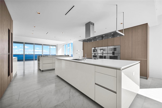 kitchen with white cabinetry, a water view, sink, and a large island