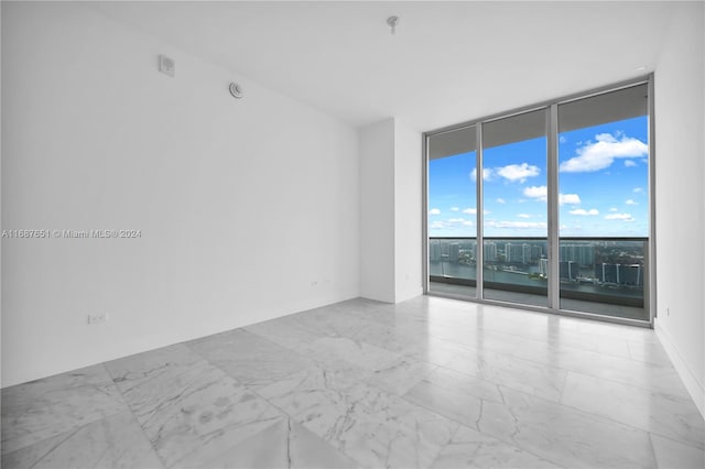 unfurnished room featuring expansive windows and a water view