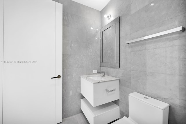 bathroom featuring tile walls, vanity, and toilet