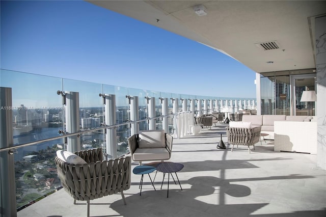 balcony featuring an outdoor hangout area, a water view, and a beach view