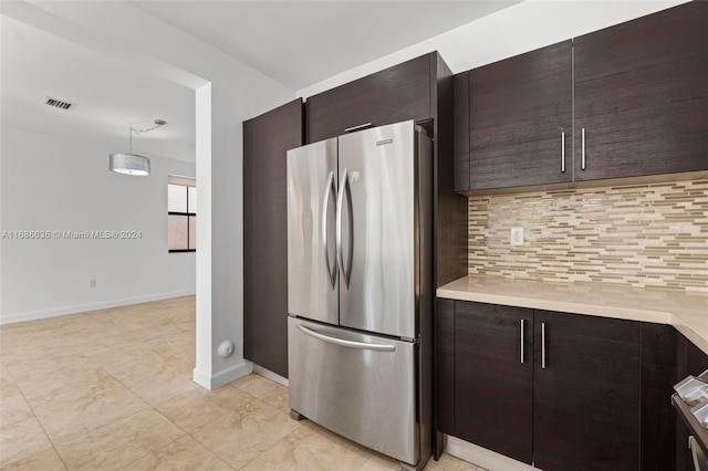 kitchen with dark brown cabinets, decorative backsplash, hanging light fixtures, and stainless steel refrigerator