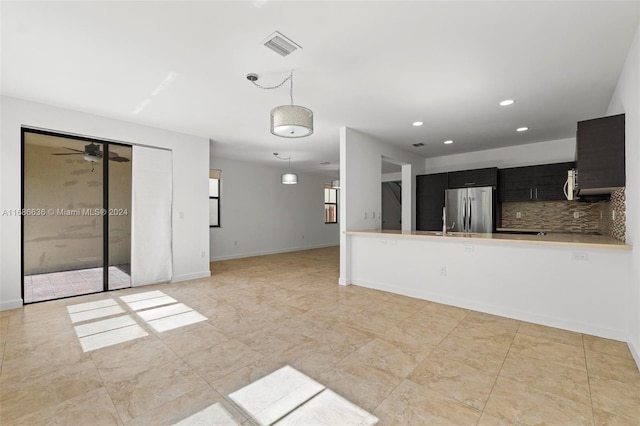 interior space featuring kitchen peninsula, stainless steel fridge, ceiling fan, decorative light fixtures, and decorative backsplash