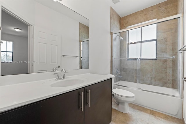 full bathroom featuring toilet, bath / shower combo with glass door, vanity, and tile patterned flooring