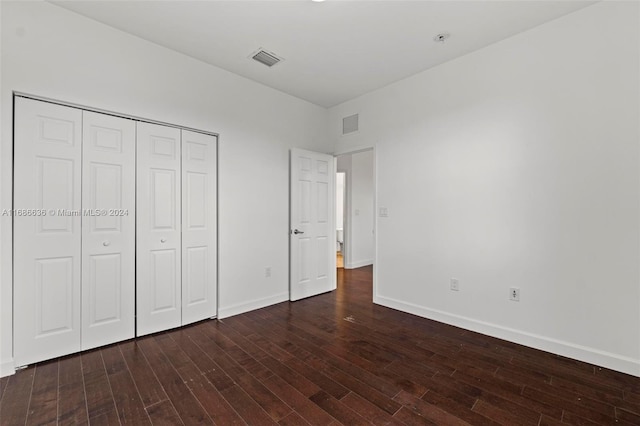 unfurnished bedroom featuring dark wood-type flooring and a closet