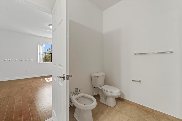 bathroom with toilet, wood-type flooring, and a bidet