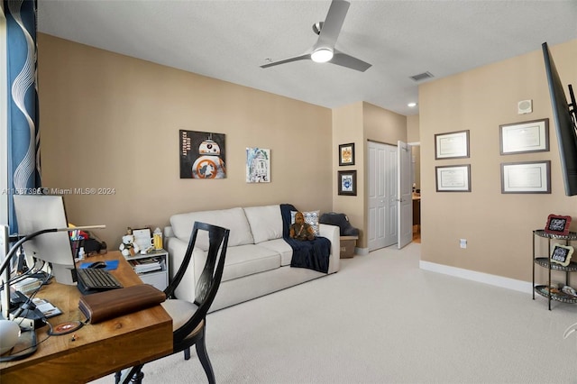 carpeted office space with ceiling fan and a textured ceiling