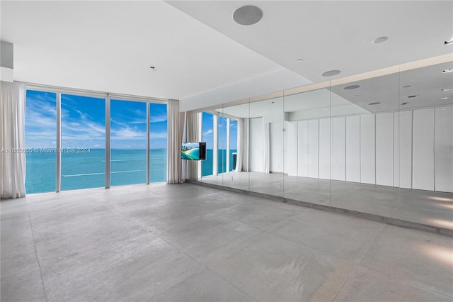 interior space featuring concrete flooring, a water view, and expansive windows