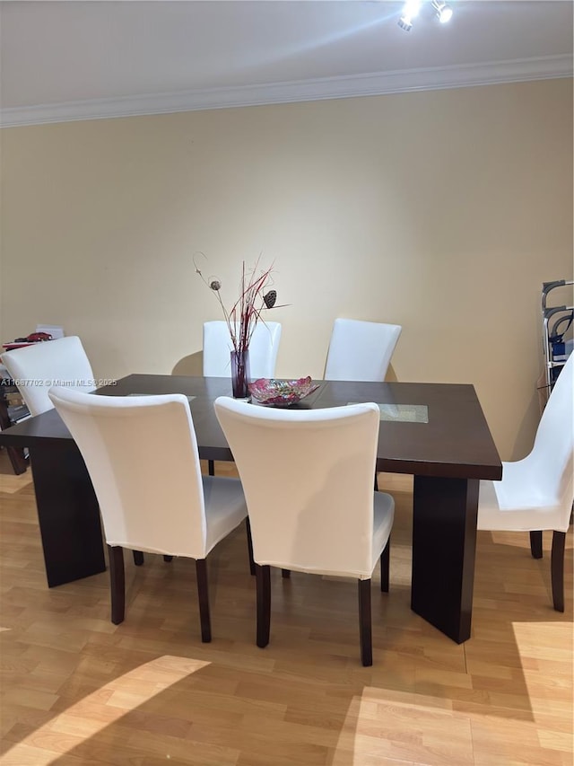 dining room with ornamental molding and light wood-type flooring