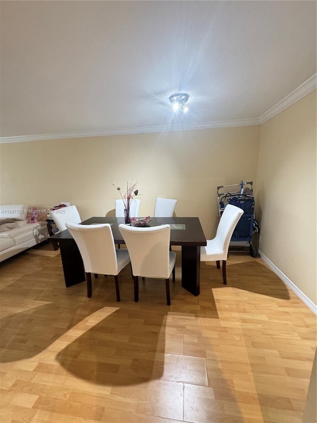 dining room with ornamental molding and light hardwood / wood-style floors