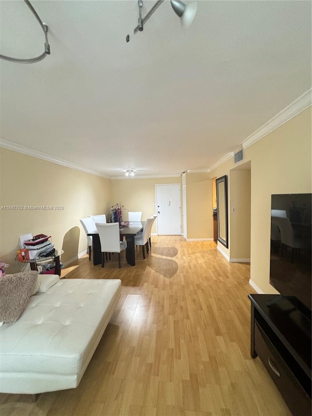 dining room with ornamental molding and light hardwood / wood-style flooring