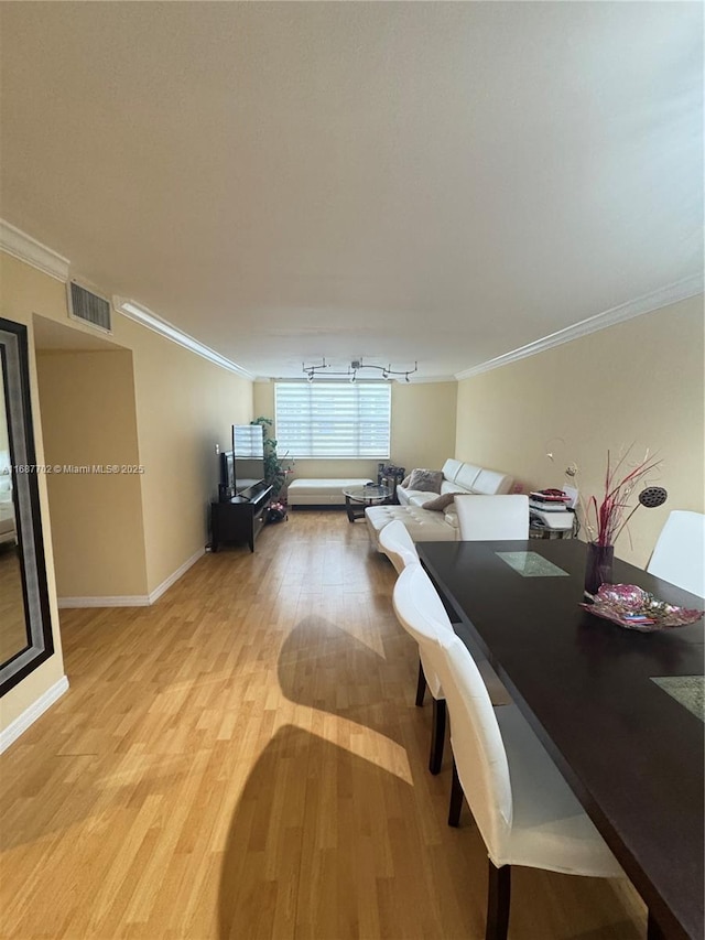 dining space featuring ornamental molding and light hardwood / wood-style floors