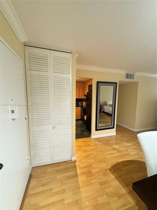 corridor with ornamental molding and light hardwood / wood-style floors