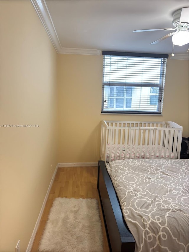 bedroom featuring crown molding, wood-type flooring, and ceiling fan