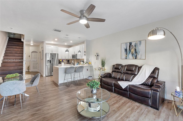 living room with light hardwood / wood-style flooring, sink, and ceiling fan