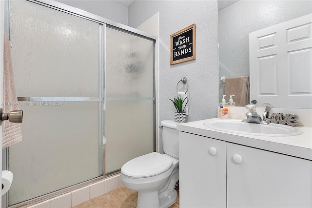 bathroom featuring vanity, toilet, tile patterned flooring, and a shower with door