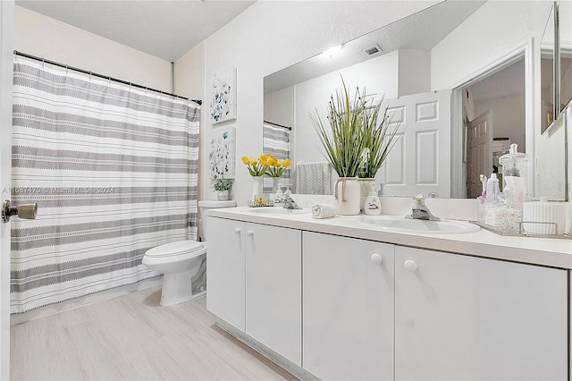 bathroom featuring hardwood / wood-style floors, a textured ceiling, walk in shower, toilet, and vanity