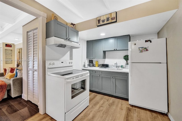 kitchen with light wood-type flooring, beam ceiling, gray cabinets, sink, and white appliances