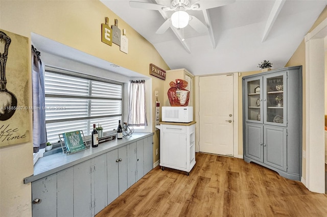 kitchen featuring light wood-type flooring, vaulted ceiling with beams, and ceiling fan