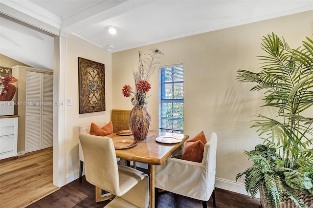 dining space with wood-type flooring, beam ceiling, and crown molding