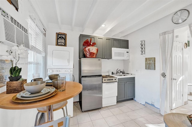 kitchen featuring white appliances, beamed ceiling, stacked washer and dryer, and gray cabinets