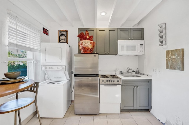 kitchen with gray cabinetry, stacked washing maching and dryer, white appliances, and beam ceiling