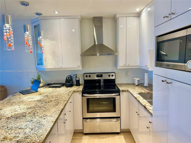 kitchen with appliances with stainless steel finishes, light stone counters, wall chimney range hood, pendant lighting, and white cabinets