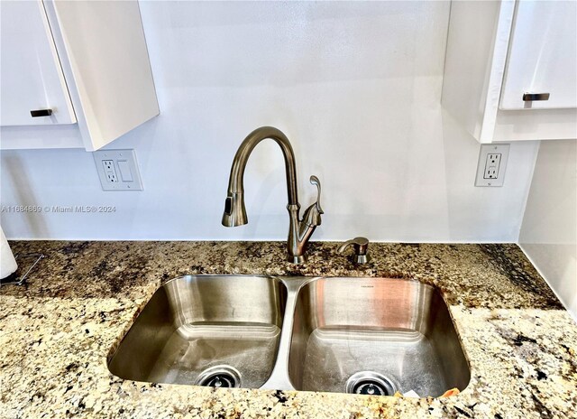 room details featuring white cabinetry, sink, and dark stone counters