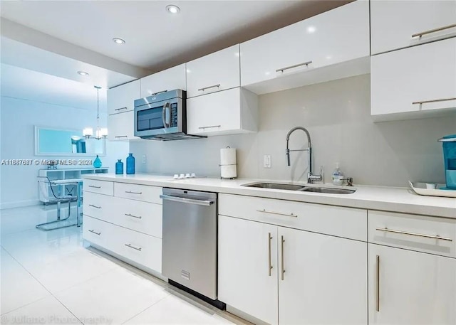 kitchen with sink, white cabinetry, stainless steel appliances, pendant lighting, and a chandelier