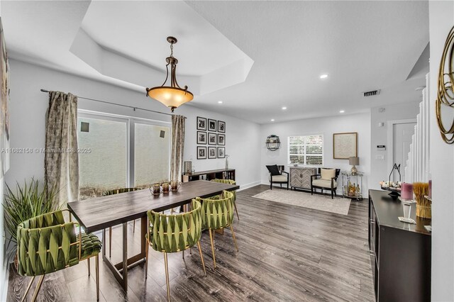 dining space with a raised ceiling, a textured ceiling, and dark hardwood / wood-style flooring