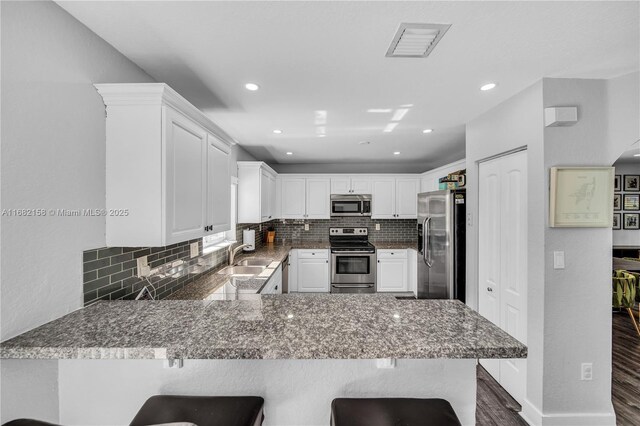 kitchen with sink, dishwasher, dark stone counters, decorative backsplash, and white cabinets