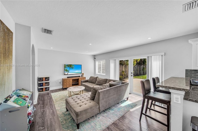 living room featuring dark hardwood / wood-style floors, a textured ceiling, and french doors