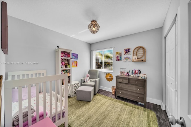 bedroom featuring dark hardwood / wood-style flooring, a crib, and a closet