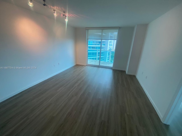 spare room featuring track lighting and dark hardwood / wood-style floors