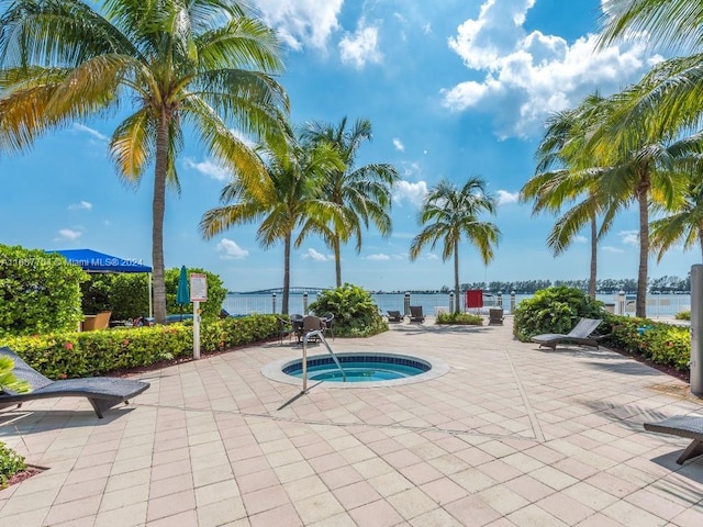 view of pool featuring a water view, a hot tub, and a patio area