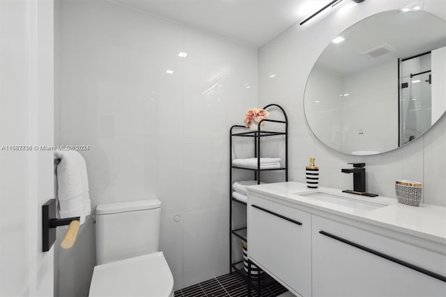 bathroom featuring toilet, vanity, tile patterned floors, and tile walls