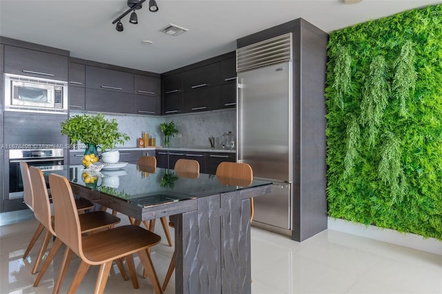 kitchen featuring decorative backsplash, built in appliances, and light tile patterned floors