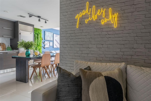 dining space featuring brick wall, light tile patterned flooring, and rail lighting