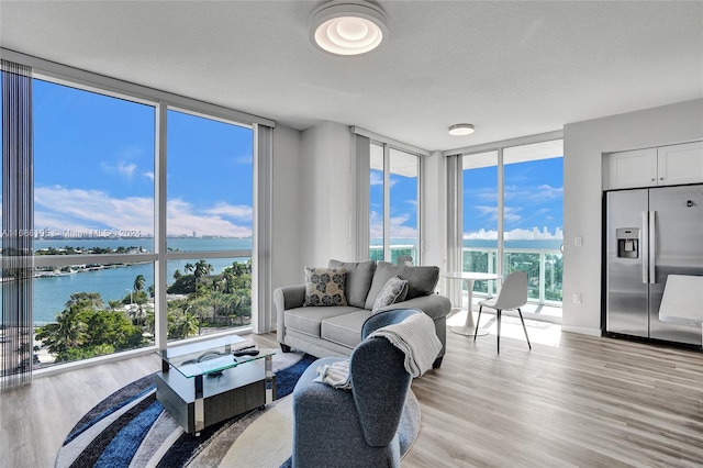 living room with a water view, plenty of natural light, and a wall of windows