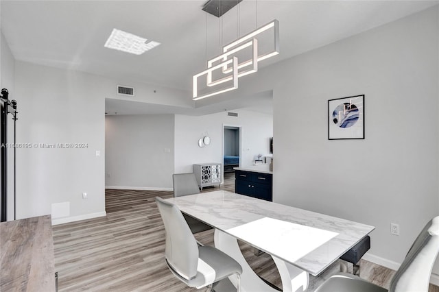 dining space with a barn door and light hardwood / wood-style floors