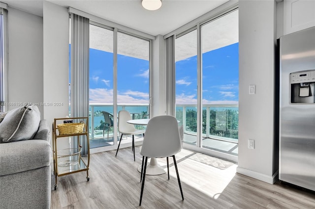 interior space featuring a water view, expansive windows, and light wood-type flooring