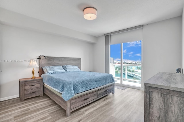 bedroom with a water view, light hardwood / wood-style floors, and access to outside