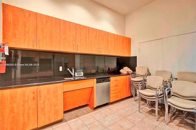 kitchen featuring stainless steel dishwasher, sink, vaulted ceiling, and light tile patterned floors