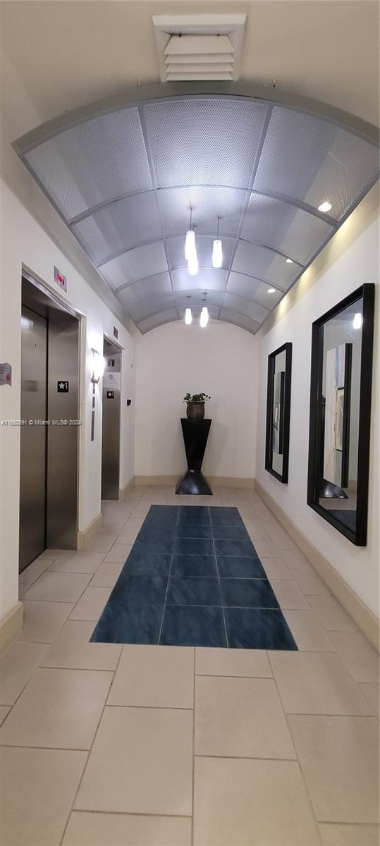 hall featuring elevator and light tile patterned floors