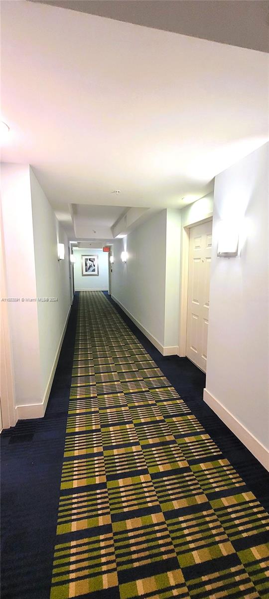 hallway featuring dark colored carpet